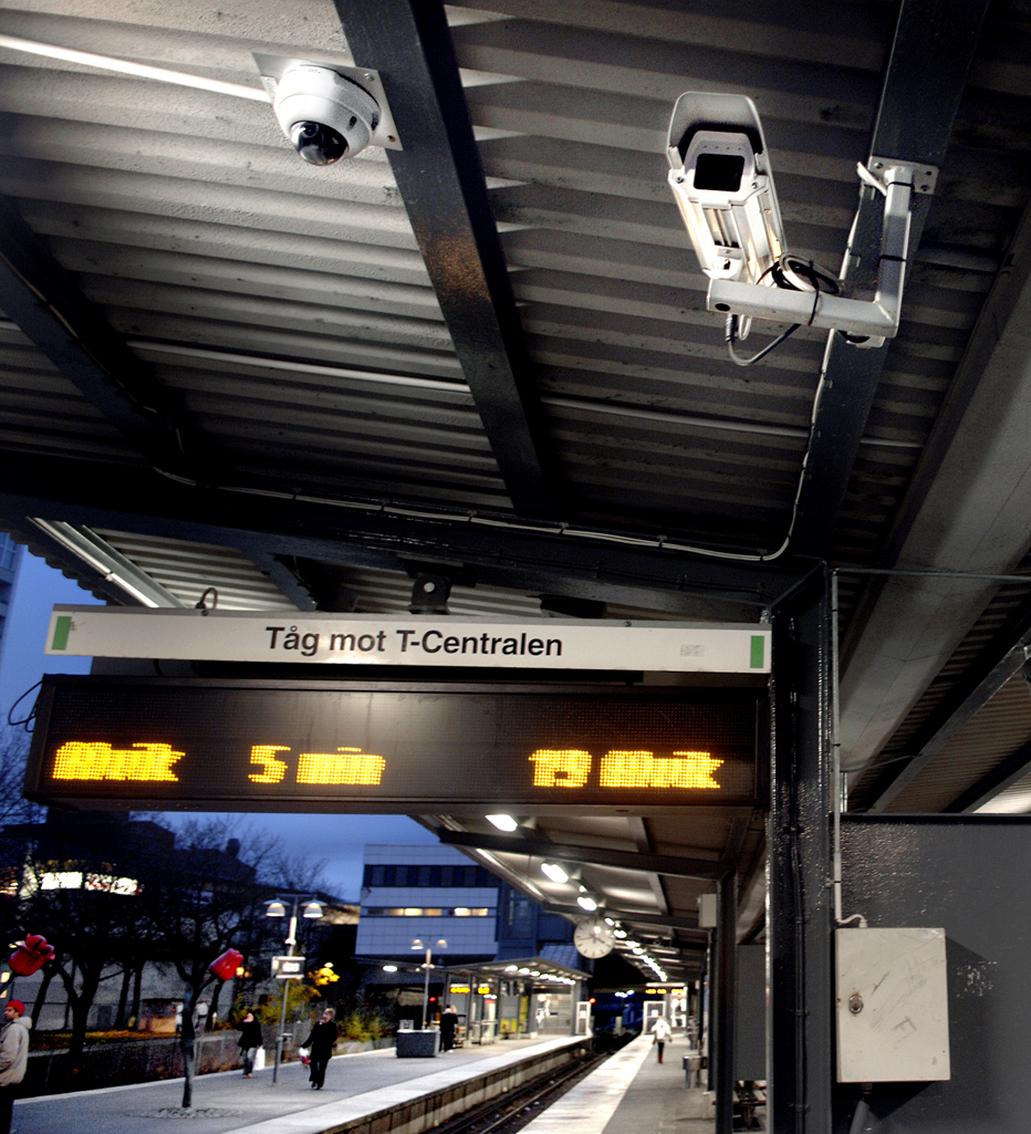 En fristående spiraltrappa i en skolbyggnad, förmodligen en högskola. Studenter vandrar runt. 